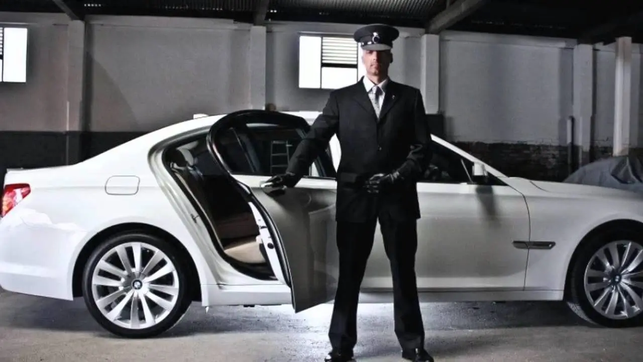 A professionally dressed Elysian Rides chauffeur holding open the door of a luxury vehicle, demonstrating impeccable service.