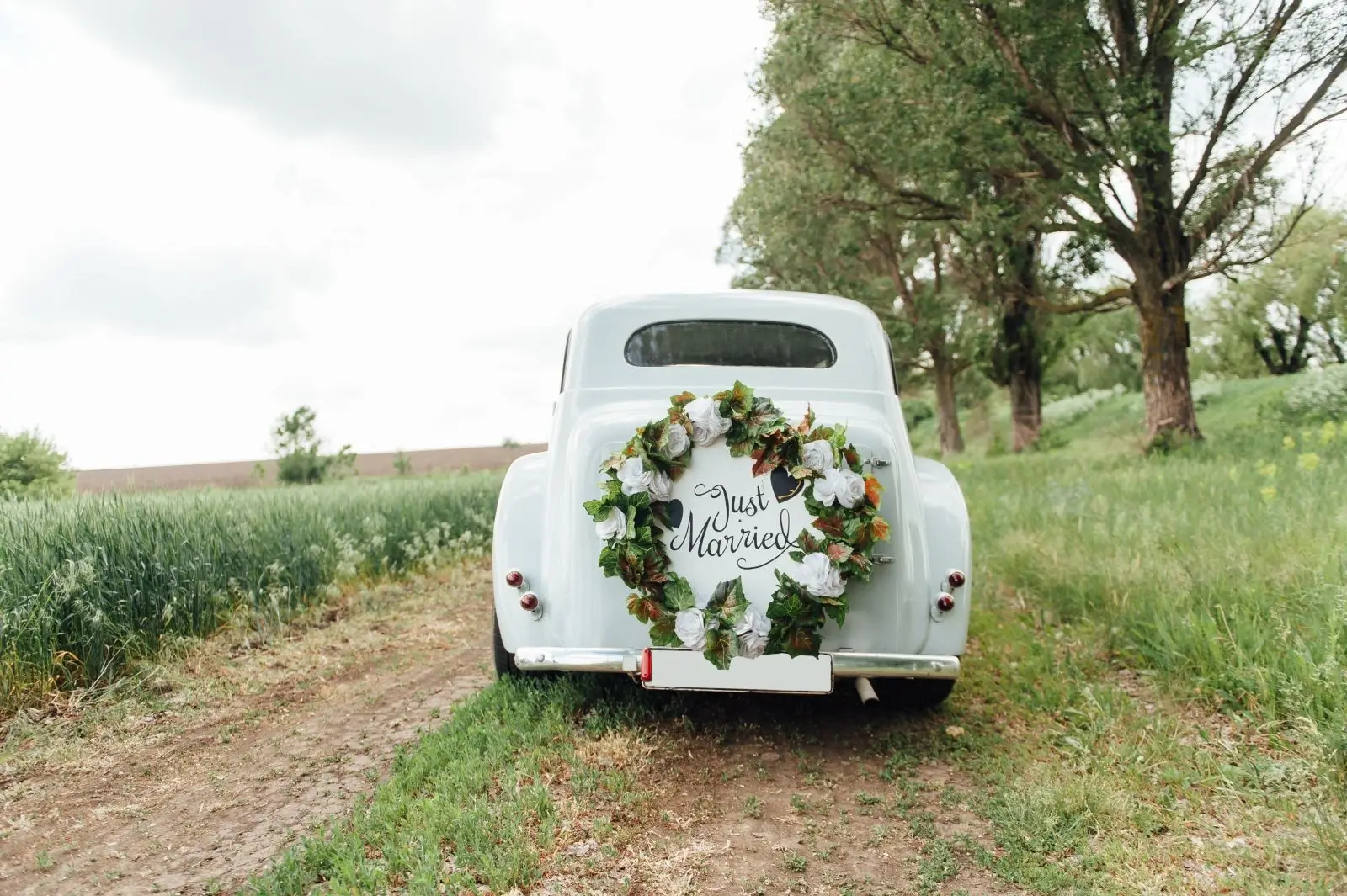 A classic wedding car adorned with a 'Just Married' sign and ribbons, ready for the couple's grand departure.